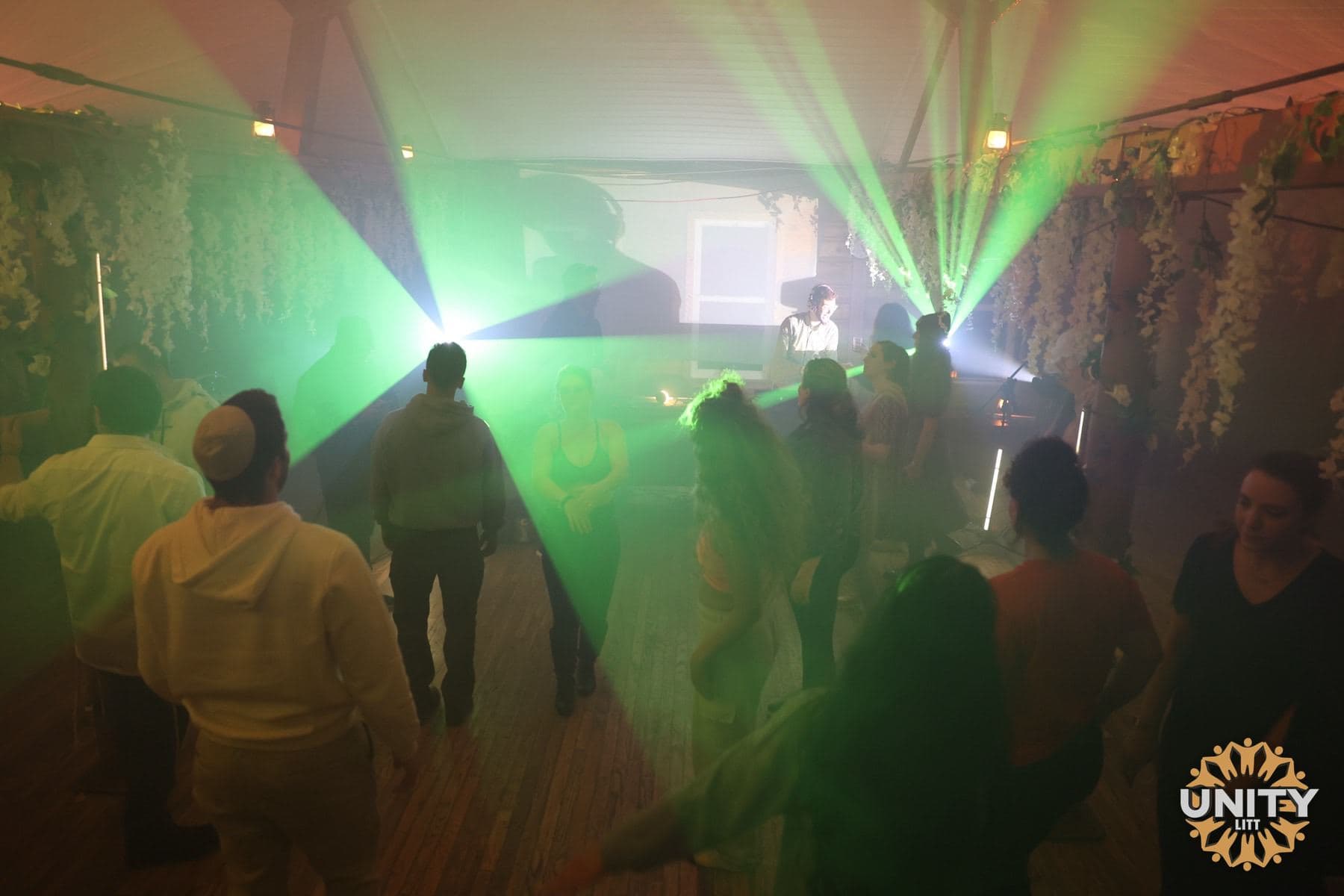 Green lasers cutting across a dance floor packed with people
