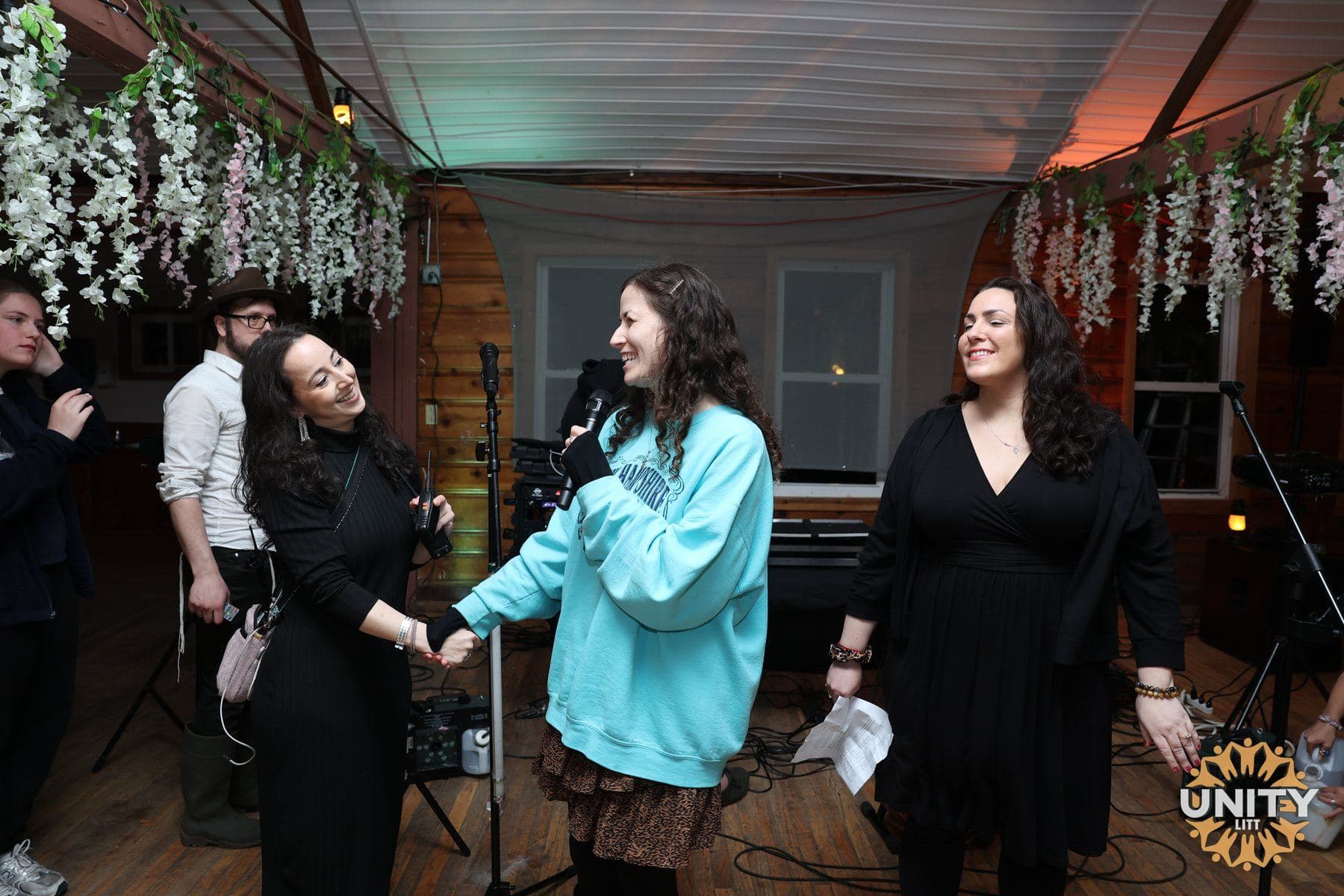 Women performing together on a small stage, mid-song