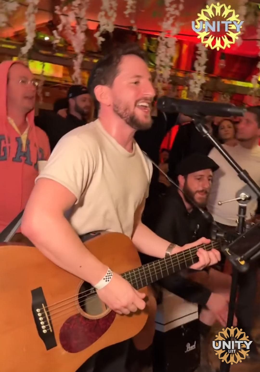 A guitarist playing acoustically surrounded by people singing along