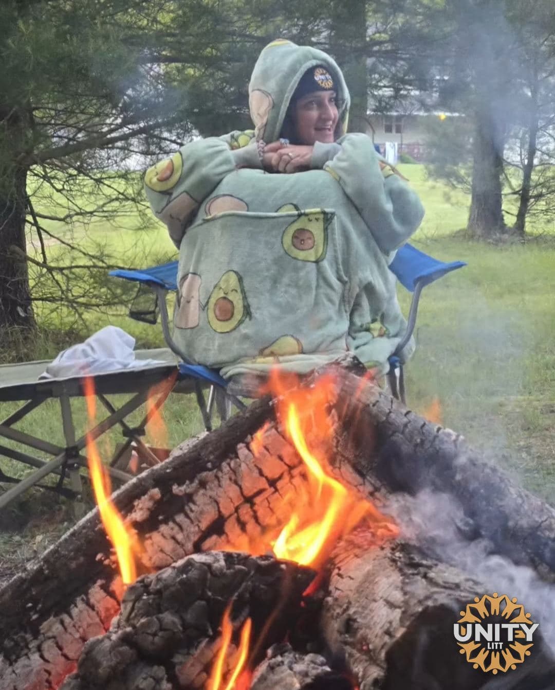 Someone wrapped in a blanket beside a bonfire