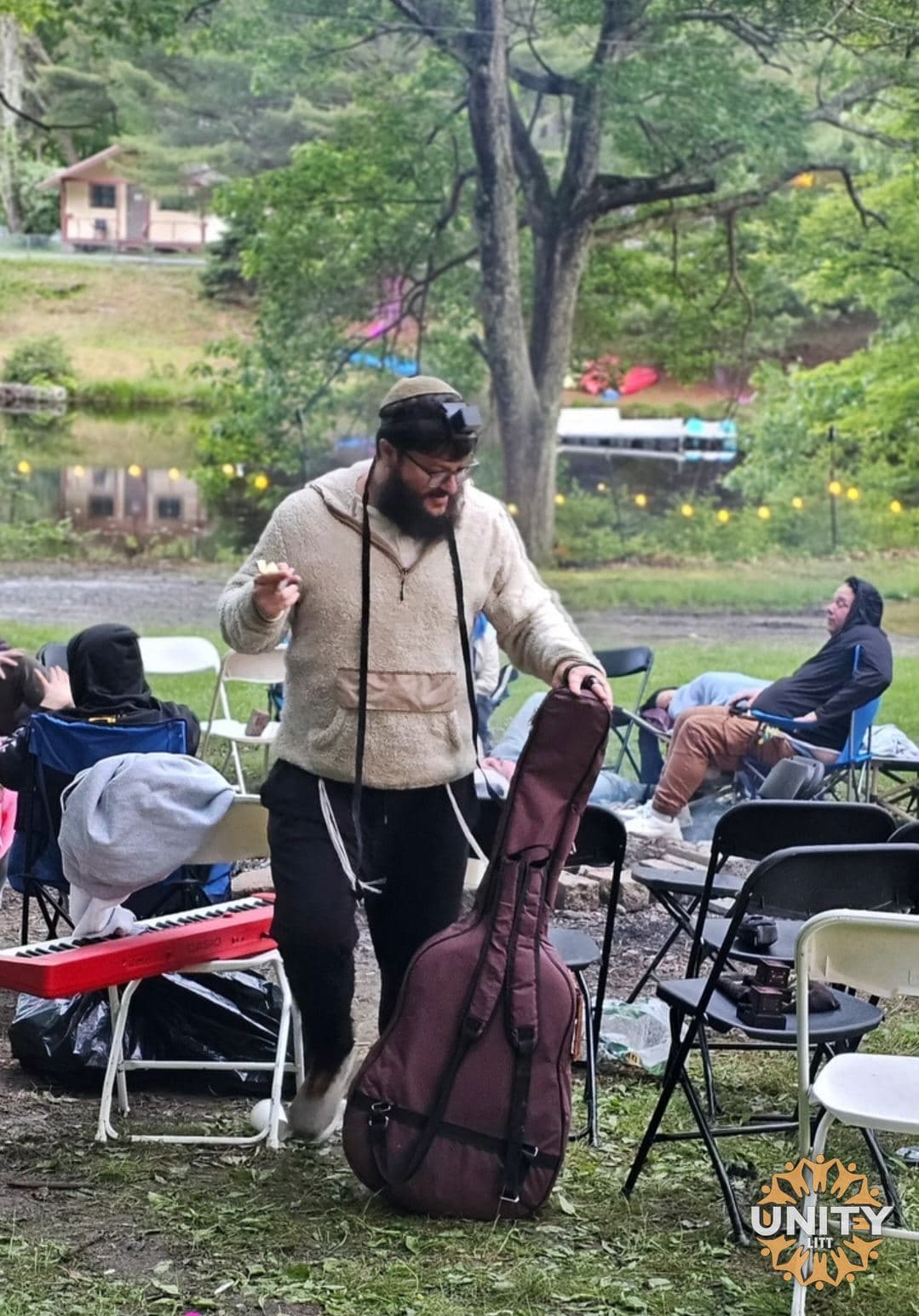 A musician playing outdoors to people sitting on camp chairs