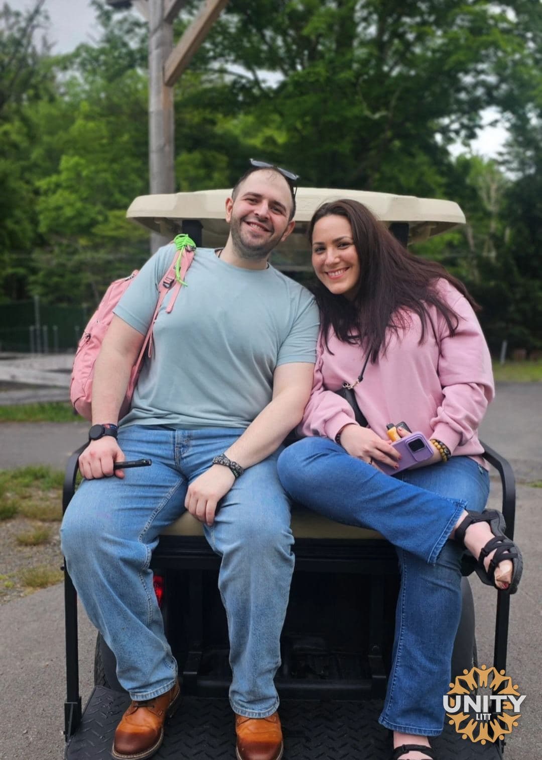 A couple sitting together on the back of a golf cart