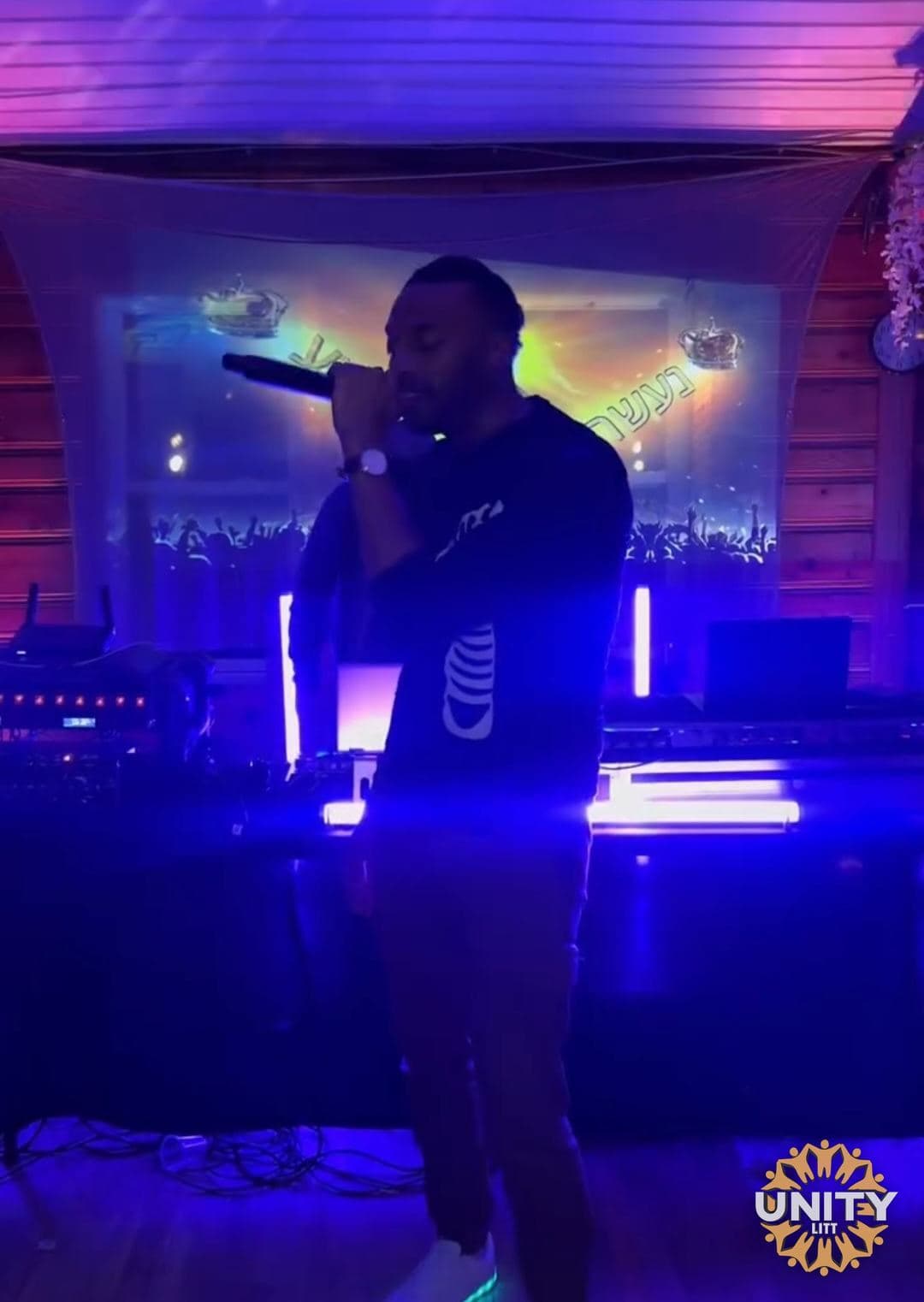 A performer on a blue-lit stage with the mic raised