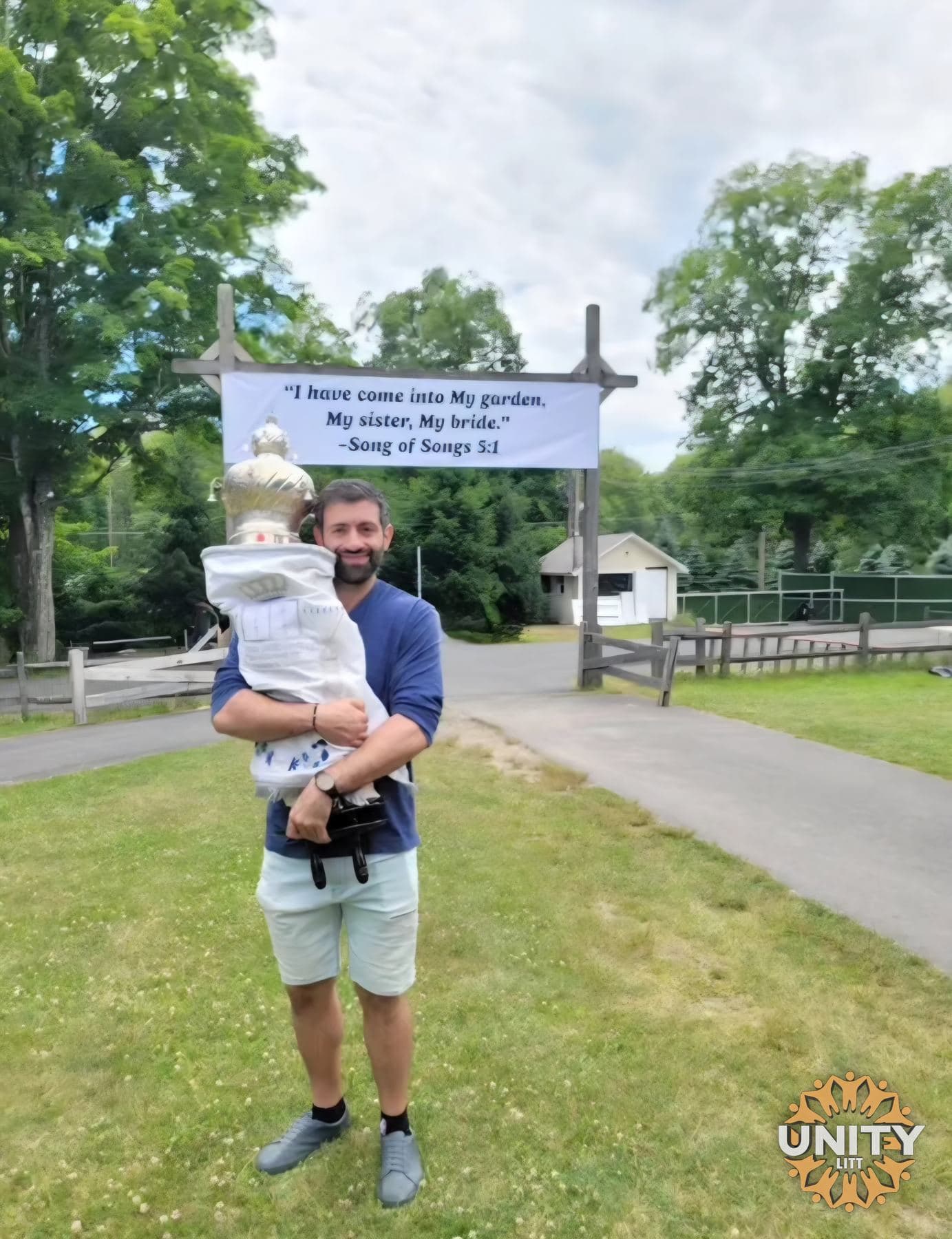 A man carrying a small child past the sign at the entrance
