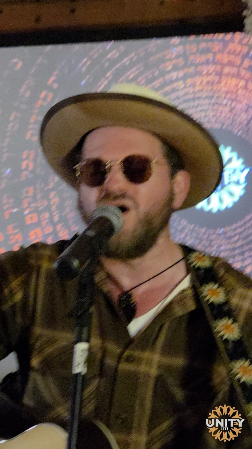 A musician in a wide-brimmed hat singing into the microphone
